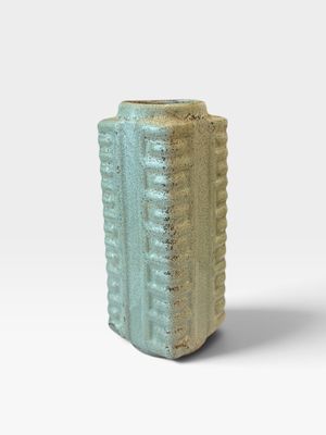 un petit vase posé sur une surface blanche