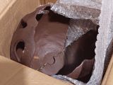 un gâteau au chocolat dans une boîte en carton, enveloppé dans du film alimentaire
