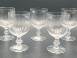 six empty wine glasses are lined up on a table