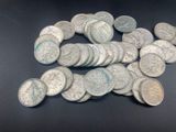 pile of silver coins sitting on a table with a black background