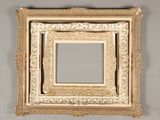 an ornate gold frame with a mirror on the wall