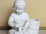 a white statue of a child sitting on the floor