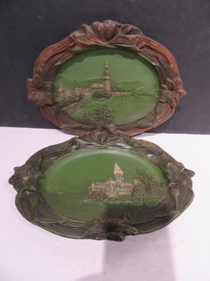 une paire d'assiettes vertes et marron ornées d'une illustration représentant un château