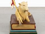 a statue of a sheep sitting on top of a book