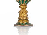 a green and gold vase sitting on a white surface