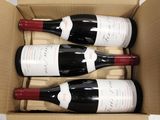 three bottles of wine in a cardboard box on a table