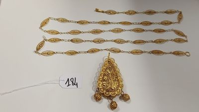 trois colliers en or et une paire de boucles d'oreilles posés sur une table