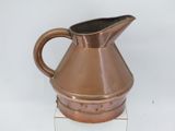 a small copper pitcher sitting on top of a white table