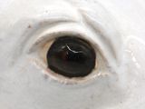 a close up of a white vase with a black eye