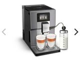 une machine à café argentée, avec deux tasses de café à côté