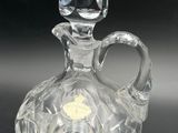 an image of a clear glass bottle with a handle on a black surface