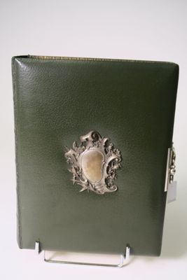 a green book with a metal frame and a picture on it