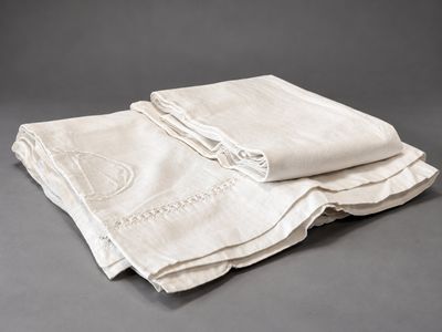 trois serviettes en lin pliées sur un fond gris