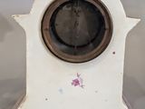 a small white clock with a brown face on a table