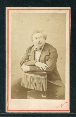 portrait d'un homme en costume et nœud papillon, assis sur une chaise