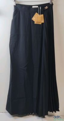 a black skirt hanging on a hanger in front of a white wall