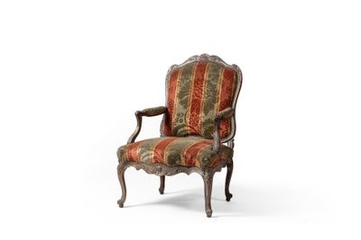 une vieille chaise dont le dossier et les accoudoirs sont recouverts d'un tissu rayé
