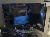 un téléviseur à écran plat posé sur un bureau, à côté d'une télécommande