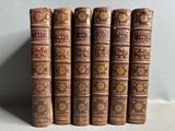 cinq vieux livres sont alignés les uns à côté des autres sur une étagère