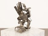 sculpture en métal argenté représentant un homme tenant une guitare, posée sur un socle blanc