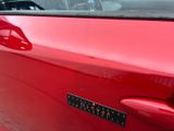 a close up of a red car with a sticker on it