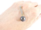 a woman ' s hand holding a ring with a black pearl on it