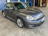 La Coccinelle Volkswagen est garée dans un garage, devant une porte de garage bleue.
