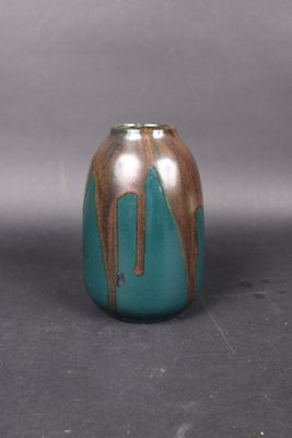 a blue and brown vase sitting on a gray surface
