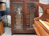une armoire en bois avec une porte vitrée, à côté d'un piano