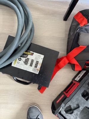 un aspirateur et un sac posés par terre à côté d'une paire de chaussures