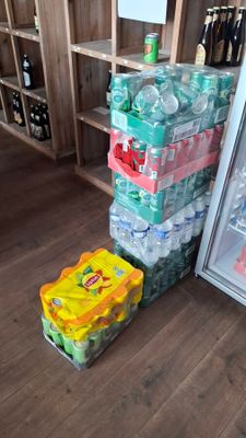 many bottles of water sitting on the floor next to a refrigerator