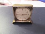 une petite horloge posée sur une table, elle-même posée sur une table