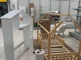 un lit en bois dans une chambre au sol carrelé de blanc