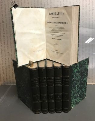 un livre ouvert posé sur une table à côté d'une pile de livres