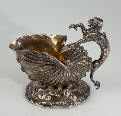 a silver vase with a dragon and a shell on it