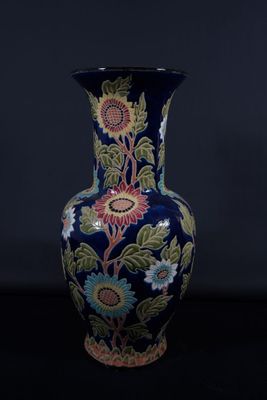 un vase bleu orné d'un motif floral sur fond noir