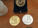 four medals on a wooden table next to a cup