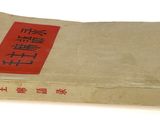 un vieux livre portant des caractères chinois, posé sur une surface blanche