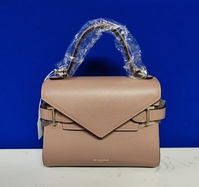 un petit sac à main beige posé sur une table blanche