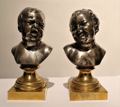 pair of bronze busts of two men on pedestals on a table