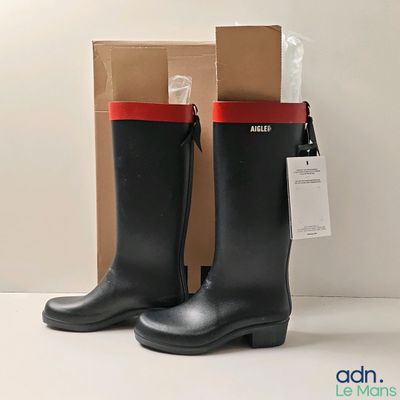 une paire de bottes de pluie noires avec des bordures rouges sur un fond blanc