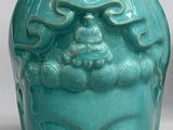 an image of a green vase with a face on it