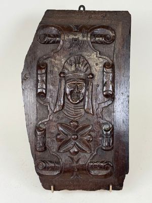 carved wooden plaque of a woman holding a sword and a shield