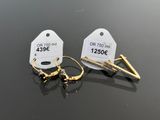 two pairs of earrings with tags on them sitting on top of a table
