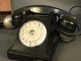 a black telephone sitting on a table next to a wooden block