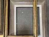 three gold picture frames sitting next to each other on top of a table