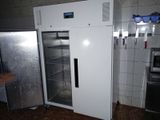 a refrigerator that is open in a kitchen with tile flooring