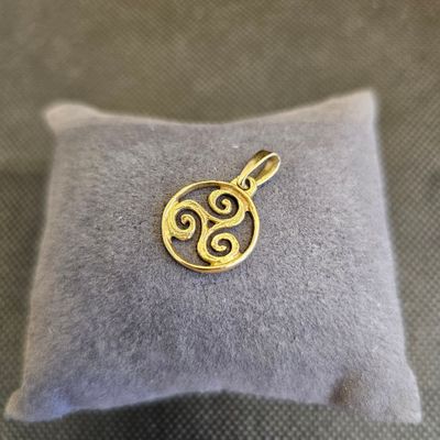 un pendentif plaqué or posé sur un coussin