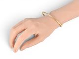 the hand of a woman wearing a gold bracelet and a gold ring
