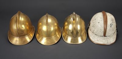 trois casques en laiton sont alignés sur un fond noir
